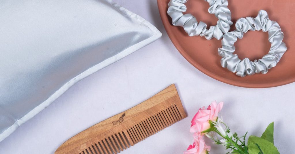 Stylish flat lay of silk scrunchies, wooden comb, and roses for a chic aesthetic. Ideal for hair care visuals.